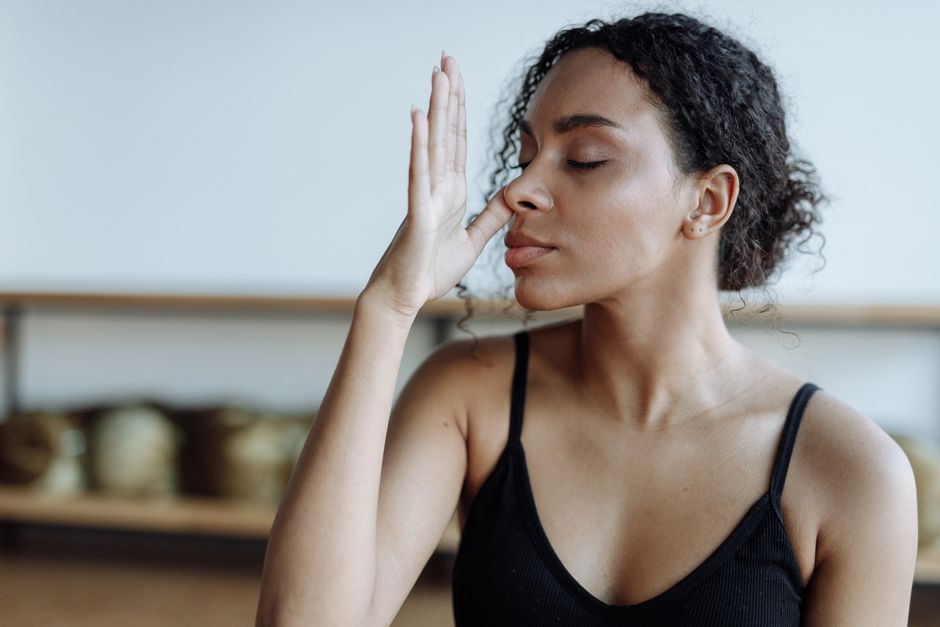 Close-up of a woman practicing yoga breathing techniques indoors, focusing on relaxation.